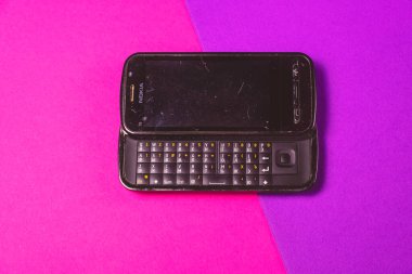 Saint-Petersburg, Rusya - 03 Mart 2020: Pembe menekşe arkaplan üzerinde eski siyah vintage cep telefonu nokia qwerty. İllüstrasyon Editörü