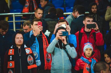 KHARKIV, UKRAINE - September 18, 2019: Football fans on the stadium support the team with phone during the UEFA Champions League match,  Ukraine
