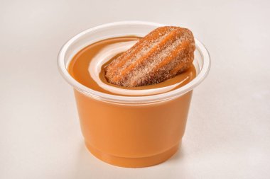 Churro with dulce de leche on plastic cup clipart