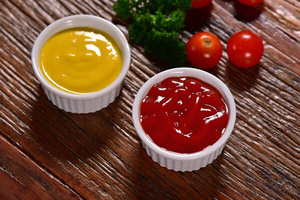 Кетчуп и горчичные миски на деревенском фоне

