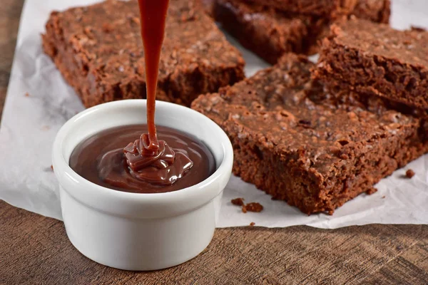 Chocolate sauce running with brownies on background