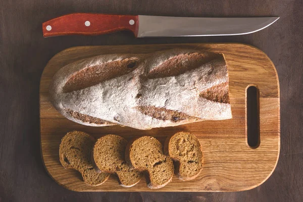 Pan negro en una tabla de cortar con un cuchillo —  Fotos de Stock