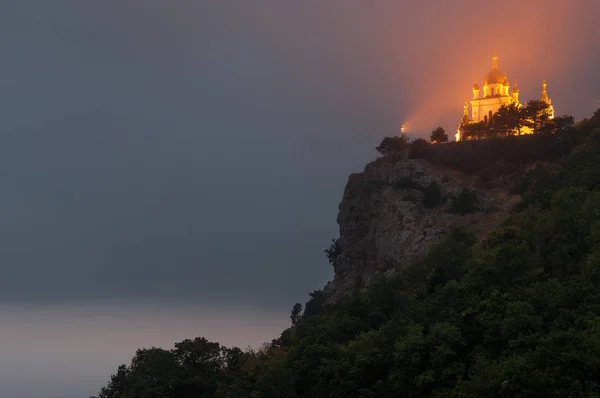 Popular scenic Church of Christ Resurrection on the cliff above Black Sea coastline near Foros, Crimea, illuminated at dusk