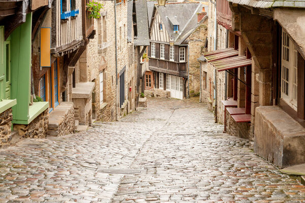 Medieval cobblestone Rue du Jerzual street with timber-framed houses and shops in historic Dinan, Brittany, France