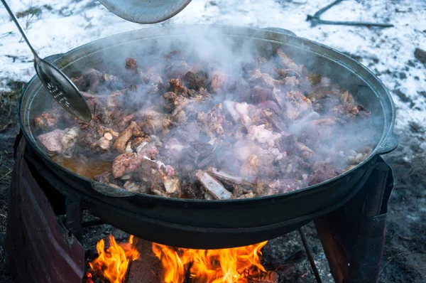 Cooking meat on fire in a large cauldron. A traditional dish.