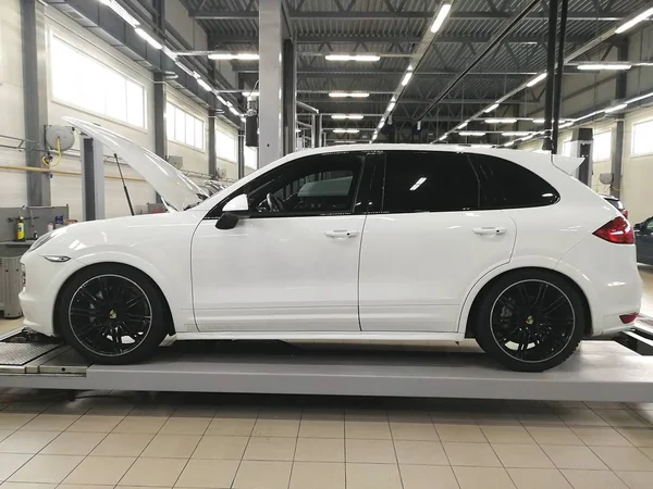 Λευκό Αυτοκίνητο Porsche Cayenne Στάση Κραδασμών Στο Κέντρο Εξυπηρέτησης Αυτοκινήτων — Φωτογραφία Αρχείου