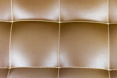 Kahverengi deri koltuğun bir parçası. Kare şeklinde dikişler. Yukarıdan görüntüle.