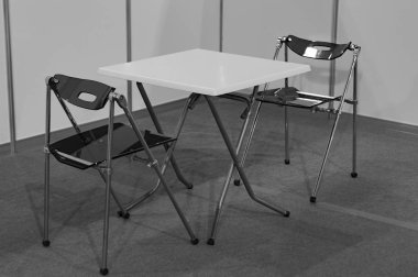 Odanın köşesinde bir masa ve iki sandalye. Siyah ve beyaz atış. Yan görünüm.