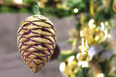 Odada Noel süsü var. Noel ağacı oyuncağı - köknar konisi. Yeşil ve altın rengi. Yazılım ve seçici odaklanma. Yakın çekim. Ön görünüm.