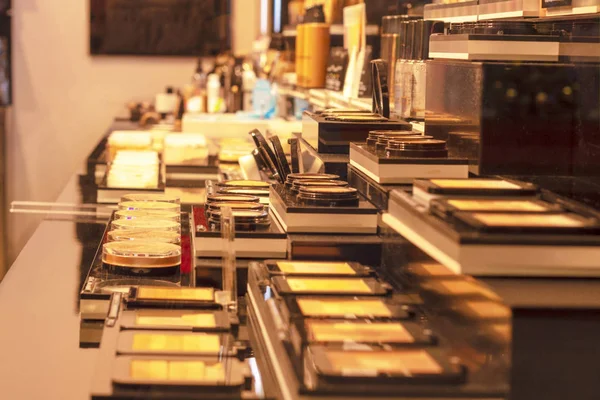 Cosmetics and perfumes on a special table. Software and selective focus. Gold soft colors. Side view.