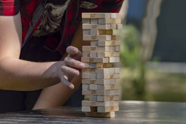 Adam Jenga Kulesi 'nden ahşap bir blok öne çıkıyor. Yan görünüş. Kavram. Surgut, Rusya - 25 Eylül 2019.