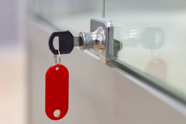 Gri ofis cam mobilyalarının üzerinde kırmızı etiket ile kilitle. Yan görünüm.