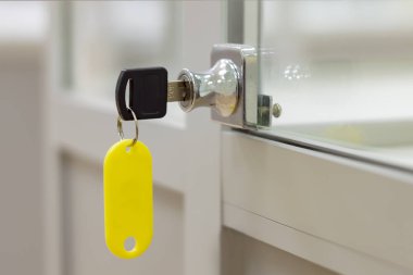 Gri ofis cam mobilyalarının üzerinde sarı etiketli anahtarla kilitle. Yan görünüm.