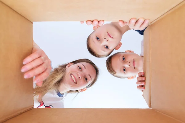 Una giovane madre con i suoi figli guarda nella scatola . — Foto Stock