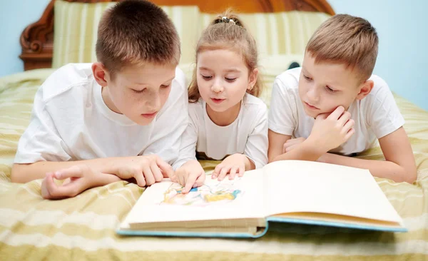 Tre bambini stanno esaminando solo un libro — Foto Stock