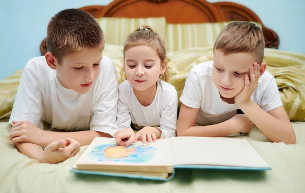 Tre bambini stanno esaminando solo un libro — Foto Stock