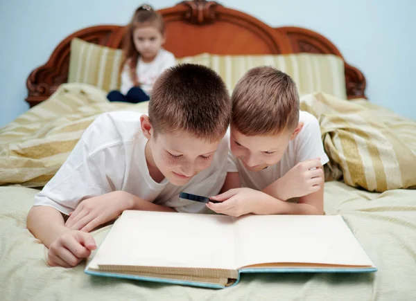 Üç çocuk sadece bir kitaba bakıyor. — Stok fotoğraf