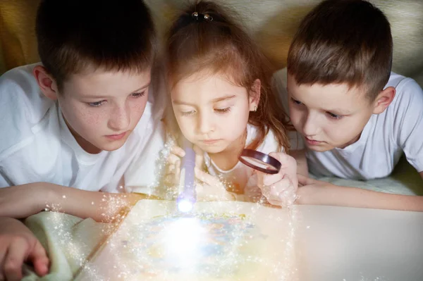 Three children are looking into a book only — Stock Photo, Image