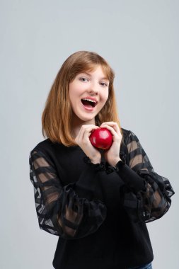Girl posing in front of the camera with an apple in her hands