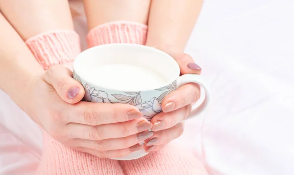 Frauenhände umhüllen frühmorgens eine Tasse auf dem Sofa — Stockfoto