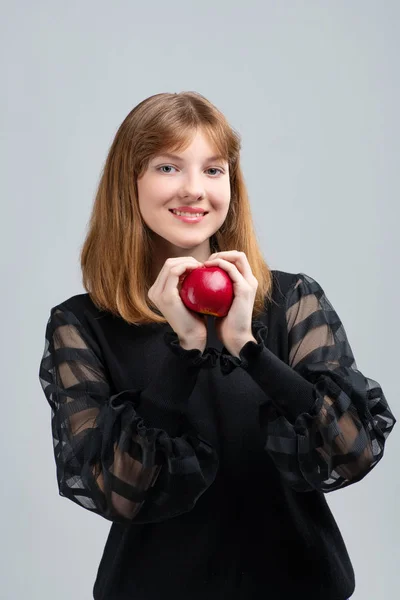 Girl posing in front of the camera with an apple in her hands — Stockfoto