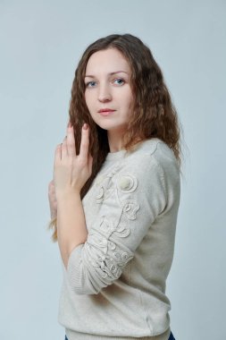 Kameranın önünde kıvırcık saçlı genç bir kadın poz veriyor.