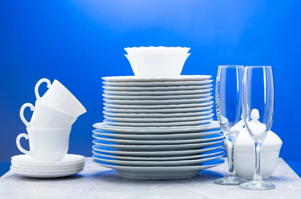 Clean plates, glasses, cups and cutlery on blue background — 图库照片