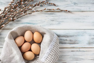 Paskalya tavuğu yumurtaları, kavramsal olarak yapay bir yuvada ahşap bir arka planda naneli.