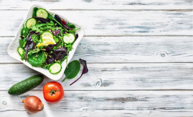 Ahşap arkaplanda yeşil salata, salatalık ve soğan..