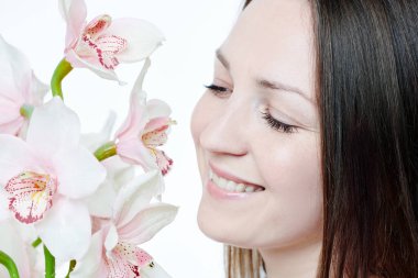 Beyaz arka planda orkide çiçeğiyle güzel mutlu bir kadın.