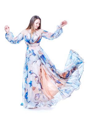 Beyaz arka planda dans eden uzun şık elbiseli bir kız.