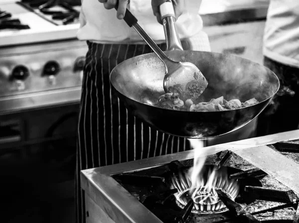 Chef cozinha com chama em uma panela de ato de fritar em um stov de cozinha — Fotografia de Stock