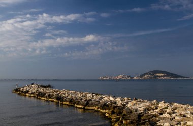 Bir güneşli sabah iskelede Balık tutma bir uzun taş iskele, Deniz Manzaralı. Akdeniz, İtalya.