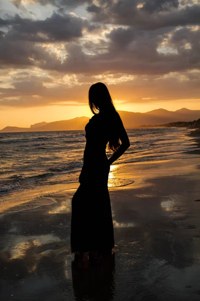 Gün batımında deniz arka plan üzerinde güzel bir kadın silüeti .