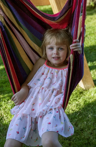 Carino bambina si trova in un'amaca all'aperto, ha un riposo in giardino . — Foto Stock