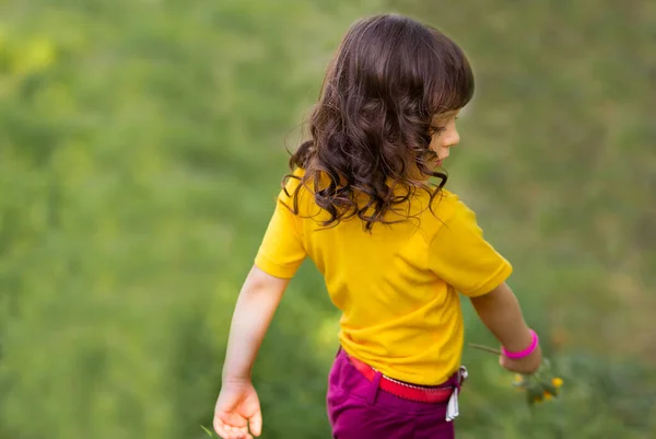 cute curly girl in a yellow T-shirt in nature is spinning.
