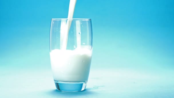 Milch Wird Ein Glas Auf Blauem Hintergrund Gegossen — Stockvideo