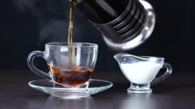 Sıcak siyah çay ve kremayı bir fincana doldurur.