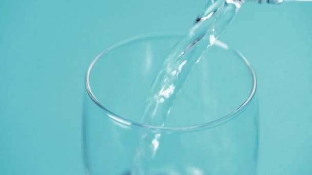 Wasser Wird Ein Glas Auf Blauem Hintergrund Gegossen — Stockvideo