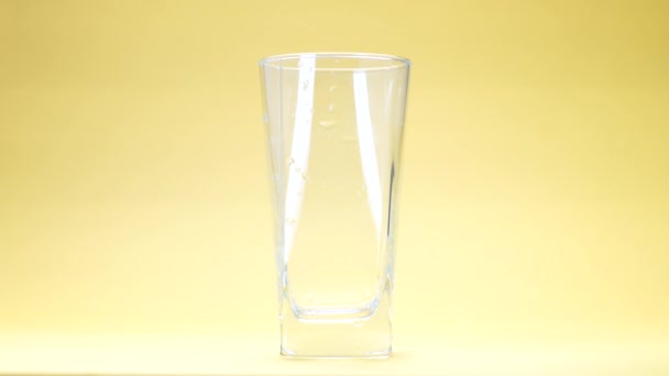 jus d'orange est versé dans un verre sur fond jaune 