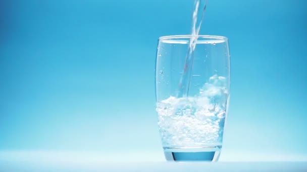 Agua Vierte Vaso Sobre Fondo Azul — Vídeos de Stock