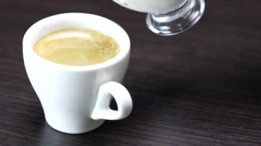Krema bir fincana doldurulur ve arka planda sıcak kahve olur.