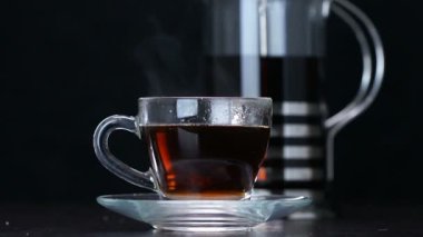 Bir fincan siyah sıcak çaya şeker dökülür.