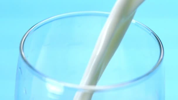 Milch Wird Ein Glas Auf Blauem Hintergrund Gegossen — Stockvideo