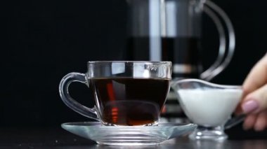Krema siyah çaya dökülüyor. Yakın plan.