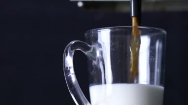 Profesyonel makineden sütlü kahve dökülüyor.