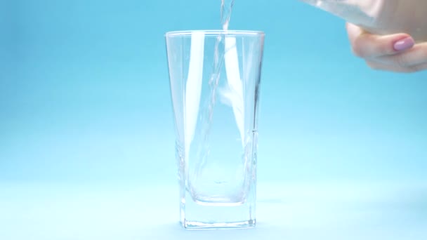 Water Wordt Gegoten Een Glas Blauwe Achtergrond — Stockvideo