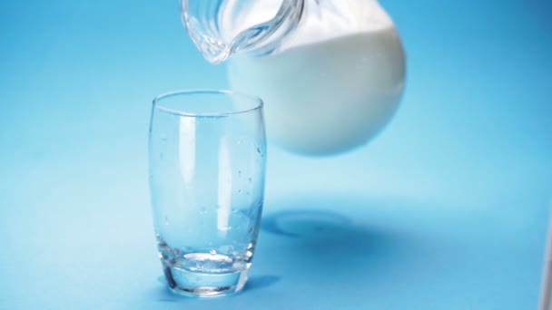 Γάλα Χύνεται Ένα Ποτήρι Μπλε Φόντο — Αρχείο Βίντεο