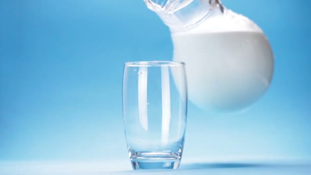 Milch Wird Ein Glas Auf Blauem Hintergrund Gegossen — Stockvideo