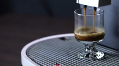 Kahve fincanındaki profesyonel makineden siyah sıcak kahve dökülüyor.